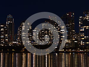 Cityscape of Vancouver downtown, Canada by night with the lights of illuminated modern buildings reflected in water.