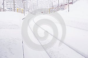 Cityscape view and closeup metal long railroad track in winter season and snow capped city with fully white foggy from snow storm