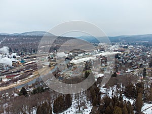 Cityscape view with the industrial chimney smoke and  the hills in the background in winter, aerial