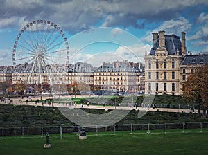 Cityscape view to the Grande Roue de Paris ferris wheel next to Louvre museum building and parisian houses, France