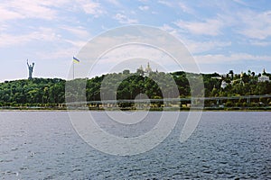 Cityscape from the water of the Mother Motherland monument and Kyiv-Pechersk Lavra on green hee