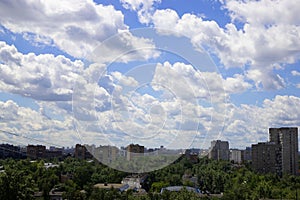 Cityscape from the window of a high-rise building in a residential area with a beautiful sky in white, fluffy clouds. The view