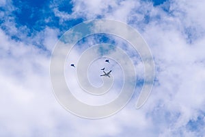 Civil aircraft escorted by two fighters on a blue sky with clouds. Selective focus, aviation concept.