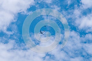 Civil aircraft escorted by two fighters on a blue sky with clouds. Selective focus, aviation concept.