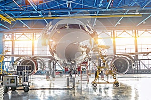 Civil airplane jet on maintenance of engine and fuselage check repair in airport hangar. Bright light at the gate