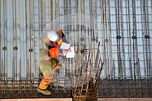 Civil engineer inspecting the work progress of a worker in a con