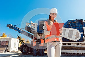Civil Engineer woman with clipboard in front of stone crusher