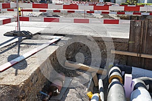 Civil engineering building site with thick pipes covered by layer of insulation foam, secured by red and white barrier planks