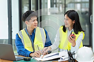 Civil engineers and architects discuss project construction together at office and holding walkie talkie