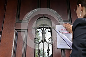 Civil servant, a woman in a jacket sticks a notice of eviction of the tenant