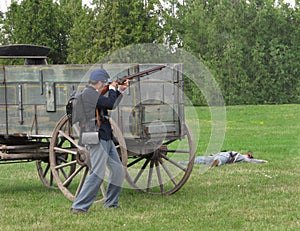 Civil War re-enactment soldier firing rifle.