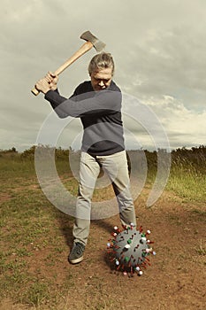 Civilian man fighting with model of coronavirus virion outdoor on meadow