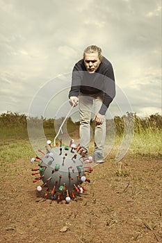 Civilian man on way looking at model of coronavirus virion outdoor on meadow