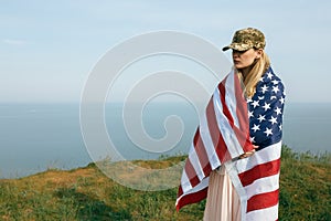 Civilian woman in her husband`s military cap. A widow with a flag of the united states left without her husband. Memorial Day to