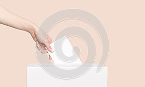 Civilized Equal Rights Concept. Female Hand Lowers Ballot In Ballot Box On Light Suntan Peach Background photo