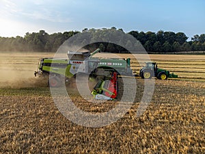 Claas 8900 harvester combine offloading to tractor in the field in Faxe, Denmark