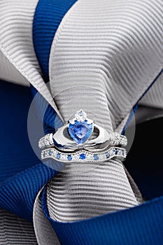 Claddagh ring with blue topaz on ribbon background