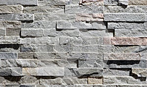 Cladding wall made of small uneven stone bricks, predominantly gray. photo