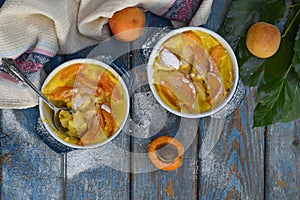 Clafouti with apricots in rameken on blue wooden background. Fruits clafoutis. Sweet casserole. Traditional French cake. Copy