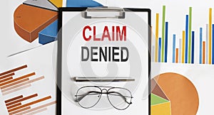 CLAIM DENIED text . Conceptual background with chart ,papers, pen and glasses, business