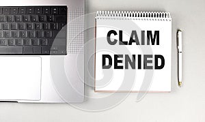 CLAIM DENIED text on notebook with laptop and pen