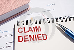 CLAIM DENIED. Text written on notepad with pen on financial documents
