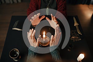 Clairvoyant and client holding hand over candle flame top view photo