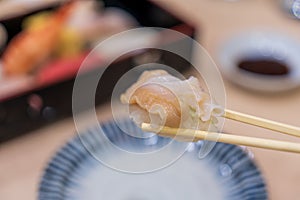 Clam sushi. Eating a sushi with soy sauce by a chop sticks