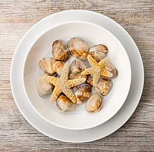 Clams and star fish in dish in wooden background