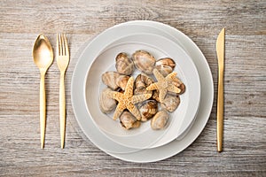 Clams and star fish in dish in wooden background