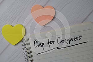 Clap For Caregivers write on a book isolated on office desk photo