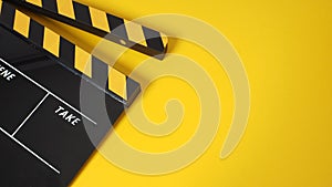 Clapper board or movie slate with black&yellow color and film roll on yellow background. It is used in video production and film