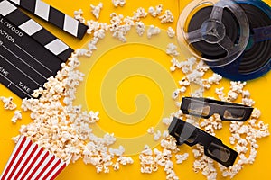 Clapperboard, 3D glasses and popcorn on yellow background