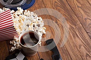 Clapperboard, film reel and popcorn on wooden background