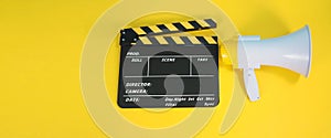 Clapperboard or movie clapper board in yellow and black color and Megaphone isolated on yellow background.