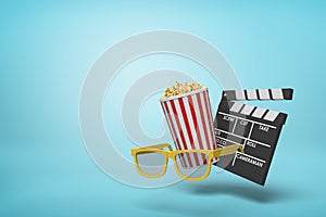 Clapperboard tipping over by popcorn tub