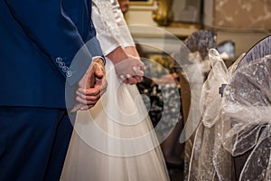 Clapsed hands of the groom and bride in the church in wedding ceremony