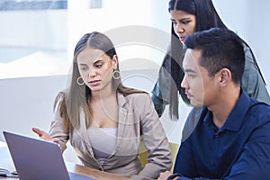 Clarifying their big plan with each other. a group of businesspeople working together on a laptop in an office.