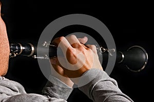 Clarinet in the hands of a man on a black background