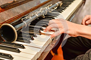 The clarinet lies on the black piano keys, the musician takes a chord on the white keys