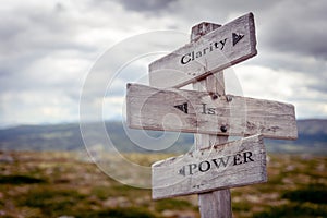 clarity is power text engraved on old wooden signpost outdoors in nature