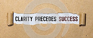 Clarity Precedes Success text on 3 piece of torn paper over green surface