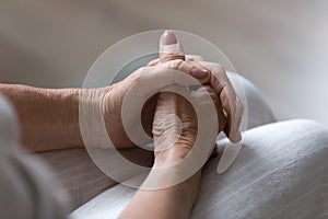 Clasped hands on lap of nervous anxious mature 60s lady