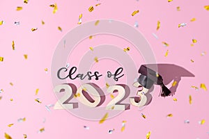 Class of 2023 concept. Numbers 2023 with black graduated cap on colored background