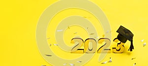 Class of 2023 concept. Numbers 2023 with black graduated cap on yellow background.