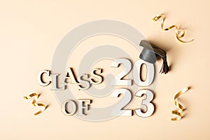 Class of 2023 concept. Wooden number 2023 with graduated cap on beige background