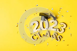 Class of 2023 concept. Wooden number 2023 with graduated cap on colored background