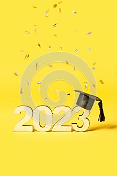 Class of 2023 concept. Wooden number 2023 with graduated cap on colored background