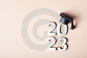 Class of 2023 concept. Wooden number 2023 with graduated cap on colored background