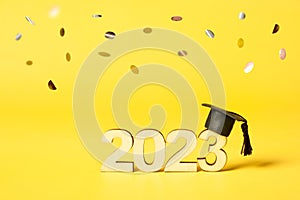 Class of 2023 concept. Wooden number 2023 with graduated cap on colored background